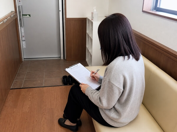 受付で問診票を書く女性